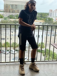 a young man standing on a balcony wearing black shorts and a headband