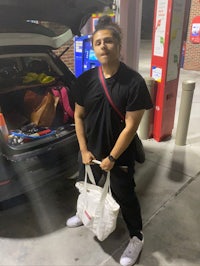 a man standing in front of a car with a bag