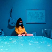 a woman wearing a face mask sitting on a blue table