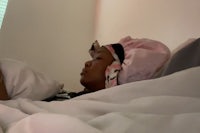 a woman laying in bed with a pink hat on her head