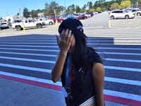 a girl with a hat covering her face in a parking lot