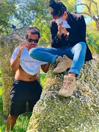 two people sitting on top of a rock