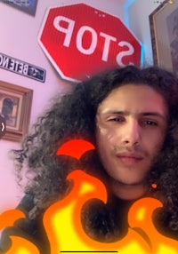 a man with curly hair in front of a stop sign