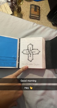 a person holding a notebook with a drawing on it