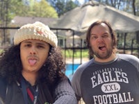 two men posing for a picture in front of a pool