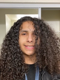 a young man with curly hair smiling for the camera